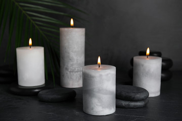 Fototapeta na wymiar Burning candles and spa stones on black table