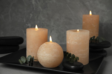 Composition with burning candles, spa stones and eucalyptus on grey background