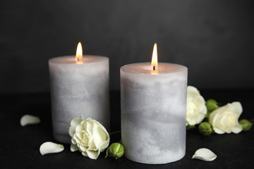 Burning candles and flowers on dark grey table