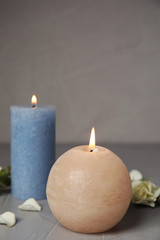 Burning candles and flowers on grey table, space for text