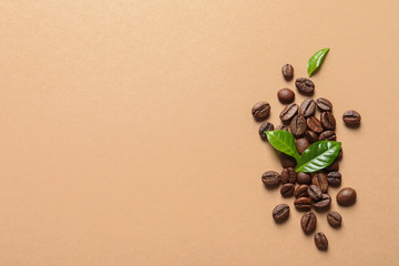 Fresh green coffee leaves and beans on light orange background, flat lay. Space for text
