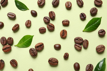 Fresh green coffee leaves and beans on light green background, flat lay