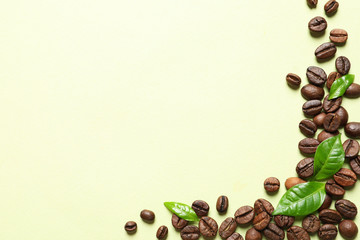 Fresh green coffee leaves and beans on light green background, flat lay. Space for text