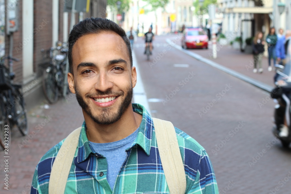 Wall mural Handsome ethnic young male smiling outdoors