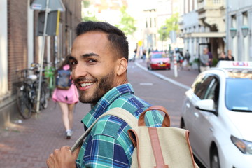 Ethnic young man looking over shoulder in busy street 