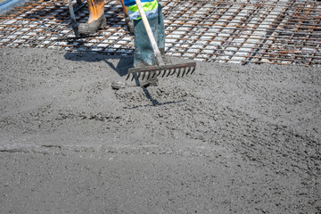 Construction worker spreading freshly poured concrete mix on the bridge with rake, repair sidewalk on bridge in Zagreb, Croatia