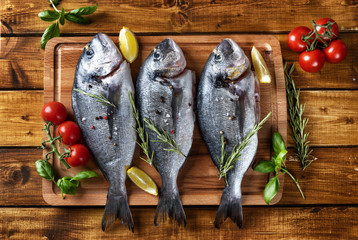 Top view of three raw dorado fishes on brown rustic background