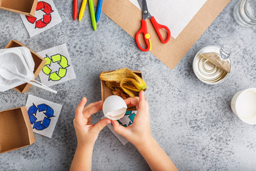 Girl hands are making recycling game in paper on grey background colourful
