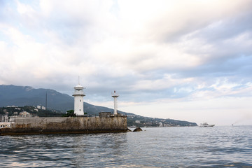 Fototapeta na wymiar Lighthouse on the Black Sea coast. Mountain view from the sea