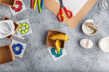 Girl hands are making recycling game in paper on grey background colourful