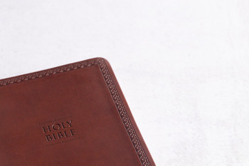 A Brown Leather Holy Bible on a White and Gray Concrete Surface