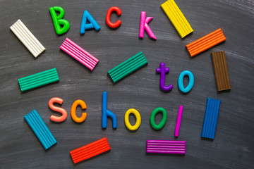 Letters from plasticine back to school on blackboard background