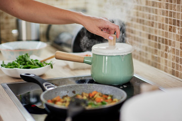 Dedicated Caucasian woman opening boiling pot. Vegetarian dinner preparation concept.