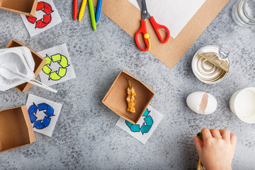 Girl hands are making recycling game in paper on grey background colourful