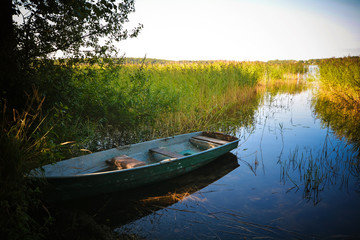 Naklejka na ściany i meble Fishing boat in a calm lake water.Old wooden fishing boat in a still lake water.