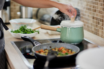 Dedicated Caucasian woman opening boiling pot. Vegetarian dinner preparation concept.