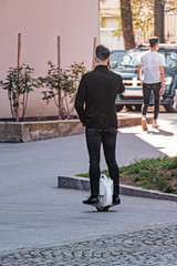 Businessman in business suit riding mono-wheel and talking on mobile