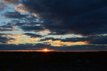 Sunset with sun and dark clouds. Dramatic view of cloudscape.