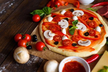 pizza with champignons, cherry tomatoes, bell peppers, salami, mozzarella and olives before baking with space for text