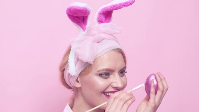 Painting egg close up. Lovely retro woman in rabbit costume. Happy woman in bunny ears with Easter egg. Funny Easter bunny woman.