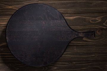 top view of black cutting board on brown table