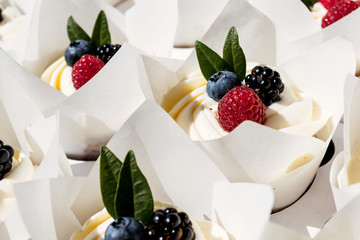Berry cupcakes with filling in box. Dessert for birthday, wedding, celebration. Decoration in chocolate tone.