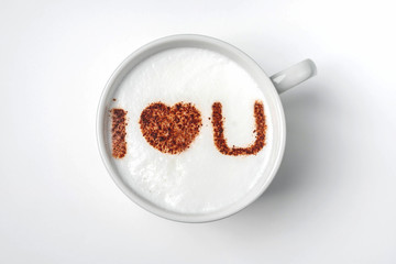 White cup of coffee with the inscription on the foam - i love you. White background, close-up, copy space. Love confession concept, heart symbol.