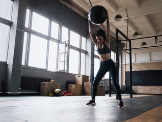 Woman doing exercise with heavy medicine ball in gym.