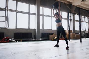 Fototapeta na wymiar Woman doing exercise with heavy medicine ball in gym.