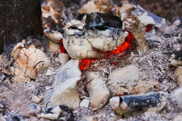 Bonfire embers texture close-up. Background of fireplace with gloving embers. Close up view on smouldering fire.