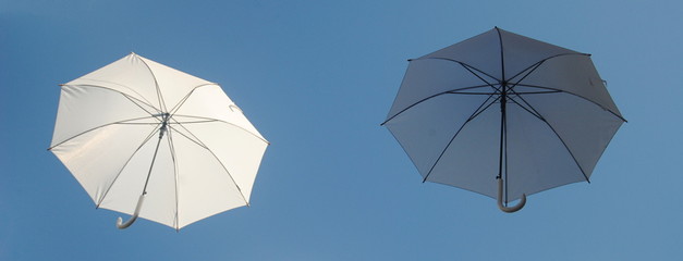 Dois guarda-chuvas brancos a flutua no céu um claro e um escuro
