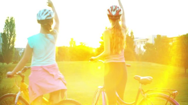 Children in helmet on bicycle rising sun salute in summer park on hillock with city on horizon . Color tone on shiny sunlight background.