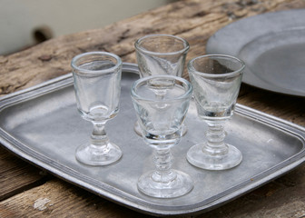Four old-fashioned goblets are placed on a metal plate.