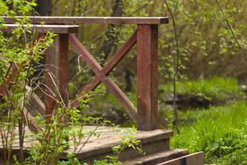 Wooden perial of the bridge through the forest river in the spring park