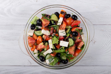 Greek salad of fresh cucumber, tomato, sweet pepper, lettuce, feta cheese and olives with olive oil
