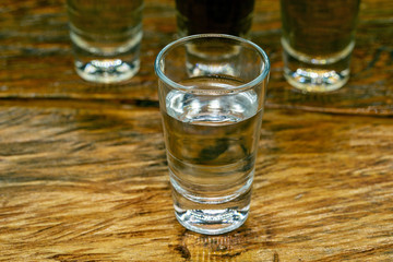 Several glasses of brazilian cachaça isolated on rustic wooden background, variations and types of brazil cachaça, typical drink from brazil.