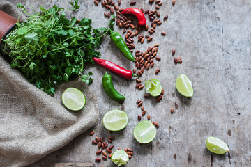 Mexican ingredients, red and green chillies, lime, beans, coriander, cilantro on a rustic table 