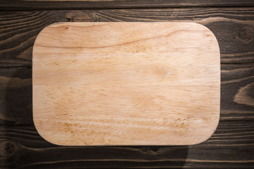top view of wooden cutting board on brown table