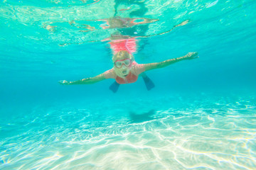 Watersport activity. Greens Pool, William Bay NP. Woman snorkeler and swims in a natural pool of Denmark Region, Western Australia. Female apnea with pink snorkeling wetsuit. Underwater scene.