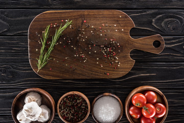 top view of cutting board, cherry tomatoes, greenery, salt, garlics and spices