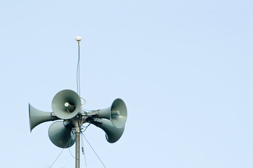 Loudspeakers mounted on a mast against the background of the sky with a spear space