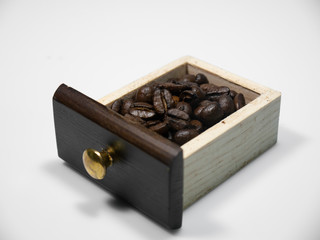 Coffee beans in the small wooden box from coffee grinder on white background. Close-up
