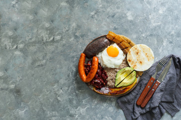 Colombian food. Bandeja paisa, typical dish at the Antioquia region of Colombia - chicharrón (fried pork belly), black pudding, sausage, arepa, beans, fried plantain, avocado egg, and rice.