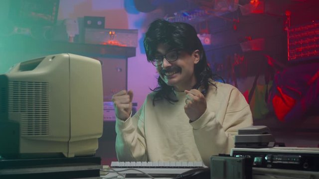 Happy computer nerd in the '80s or '90s using his personal computer. Retro scene with vintage colors and atmosphere.