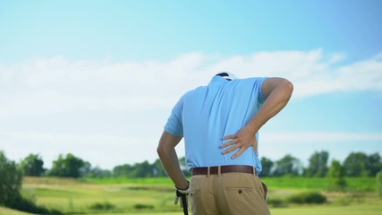 Male golfer hitting ball, unexpectedly feeling lower back pain, sport trauma