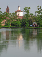 Fototapeta na wymiar landscape on the outskirts of Milan, church reflected in the navigable canal of the Naviglio Grande