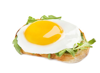 Slice of bread with fried egg and arugula on white background