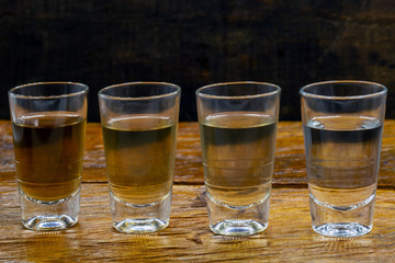 Several glasses of brazilian cachaça isolated on rustic wooden background, variations and types of brazil cachaça, typical drink from brazil.