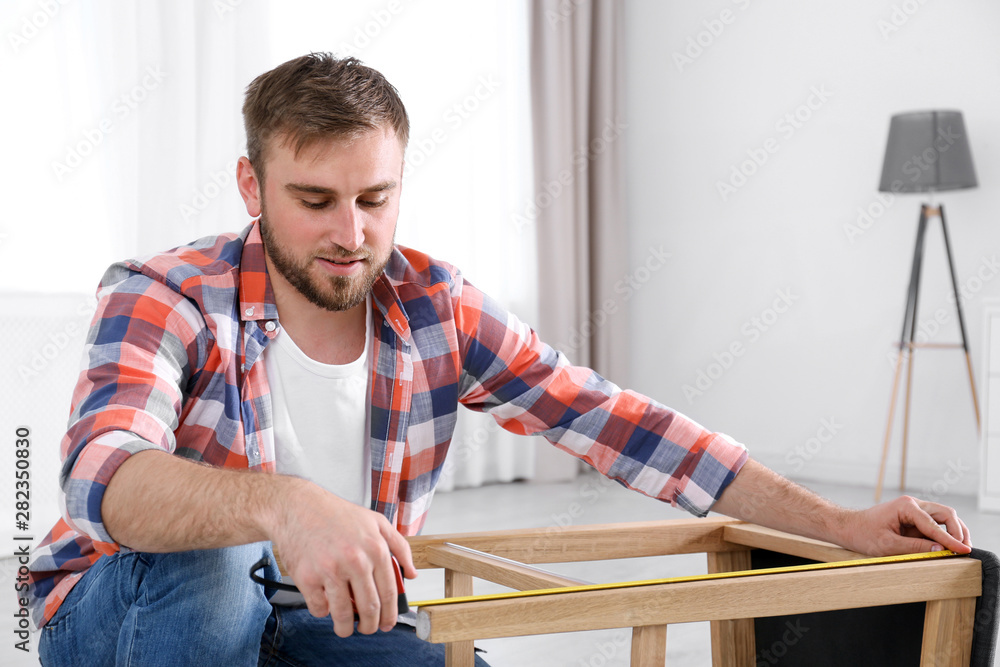 Sticker Young working man using measure tape at home