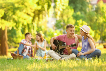 Young people enjoying picnic in park on summer day